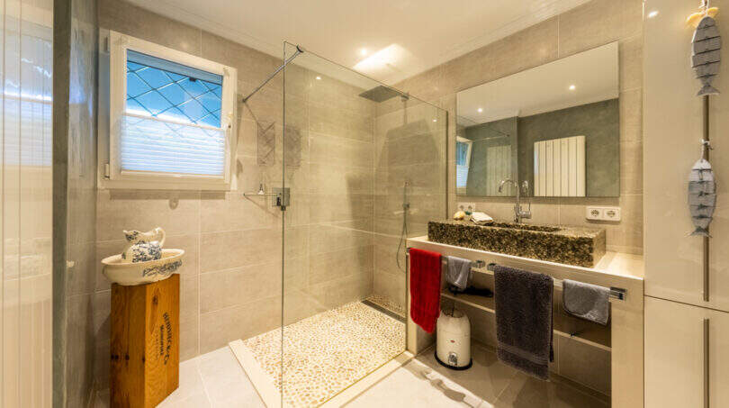 Modern bathroom of the sea view villa in Cala Murada with walk-in shower, natural stone washbasin and pebble flooring