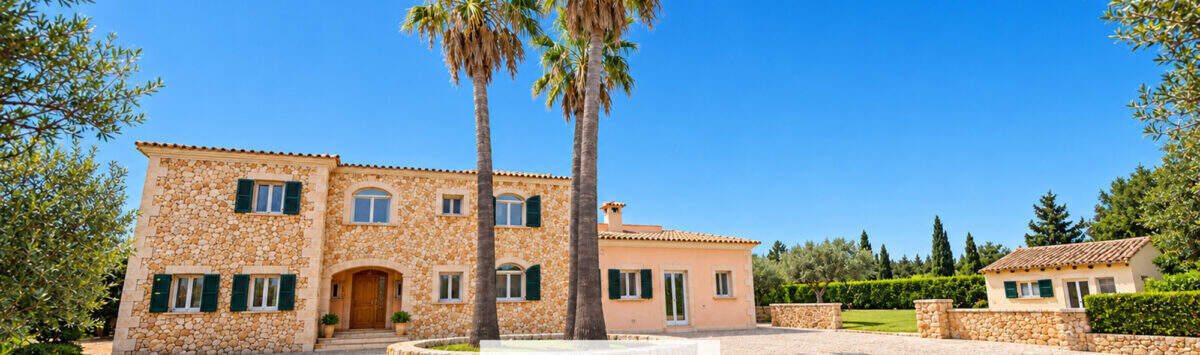 Finca Santa Maria: Steinhaus mit Palmen, Kiesauffahrt und Nebengebäuden unter blauem Himmel