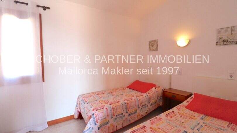 Bright bedroom with two single beds and wall lamp in finca with sea view in Son Carrió.