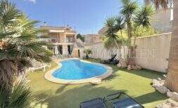 Área exterior bien mantenida con piscina ovalada, tumbonas, césped artificial y palmeras en la casa con licencia vacacional en Muro.