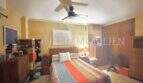 Helles Schlafzimmer der Palma-Wohnung mit Deckenventilator, bunter Tagesdecke und Holzschrank