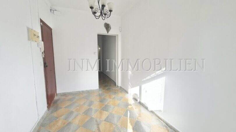 Bright hallway with checkerboard tile floor and chandelier in apartment needing renovation, Playa de Palma