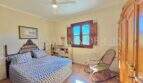 Schlafzimmer der mediterranen Finca bei Algaida mit Doppelbett, Holzschrank, Schaukelstuhl und Deckenventilator.