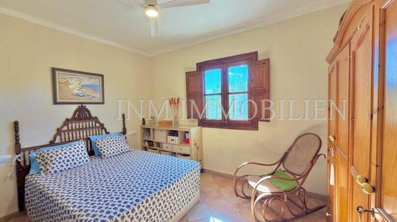 Schlafzimmer der mediterranen Finca bei Algaida mit Doppelbett, Holzschrank, Schaukelstuhl und Deckenventilator.