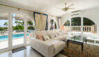Helles Wohnzimmer der Poolvilla in Cala Murada mit Bogenfenstern, weißem Ecksofa und Blick auf den Pool.