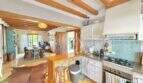 Cocina abierta con techo de vigas de madera, isla de cocina y vista al comedor en casa mediterránea Sa Ràpita