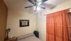 Schlafzimmer der Palma-City-Wohnung mit Doppelbett, Deckenventilator und orangefarbenem Vorhang