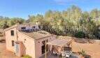 Außenansicht mediterrane Finca Algaida: rosa Natursteinhaus mit Terrassenüberdachung, Olivenbäumen und Trockenmauer.
