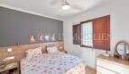 Schlafzimmer der Finca Algaida mit Doppelbett, Holzkopfteil, Deckenventilator und rustikalem Holzfenster