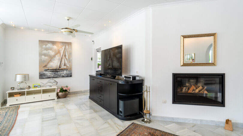 Wohnzimmer mit Marmorboden, Kamin, TV-Schrank und Segelboot-Gemälde in Villa Cala Murada