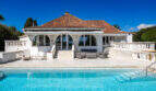 Mediterrane Poolvilla in Cala Murada mit Terrasse, Lounge-Bereich und rotem Ziegeldach unter blauem Himmel.