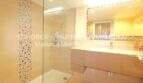 Baño moderno con ducha de plato sin escalón de vidrio, pared con revestimiento de mosaico y elegante lavabo en apartamento Cala Millor