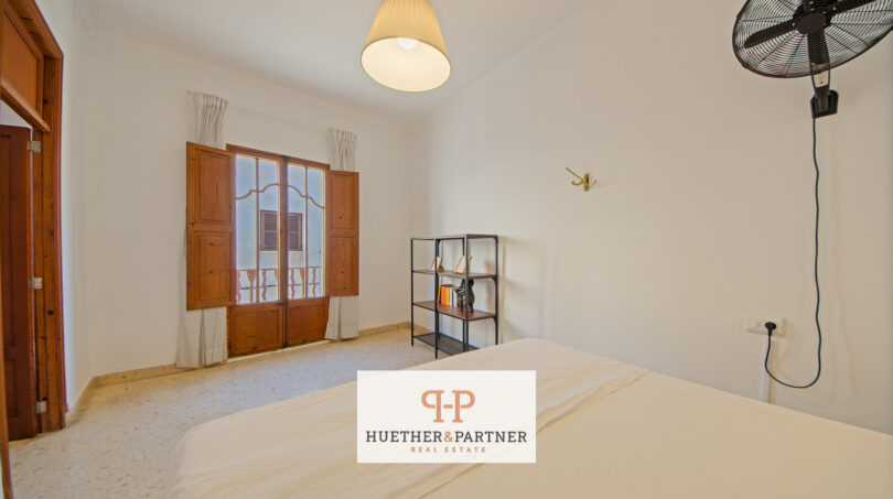 Helles Schlafzimmer im Stadthaus Manacor mit Holzfenstertüren, Deckenlampe und Wandventilator