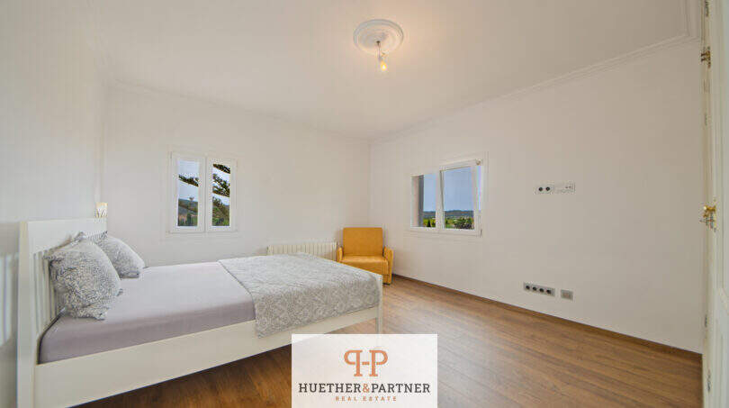 Helles Schlafzimmer der Finca Santa Maria mit Holzboden, Doppelbett und Tramuntana-Blick aus den Fenstern.