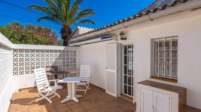 Sonnige Terrasse mit weißen Gartenmöbeln, Zierblöcken-Trennwand und Palme der Villa in Cala Murada