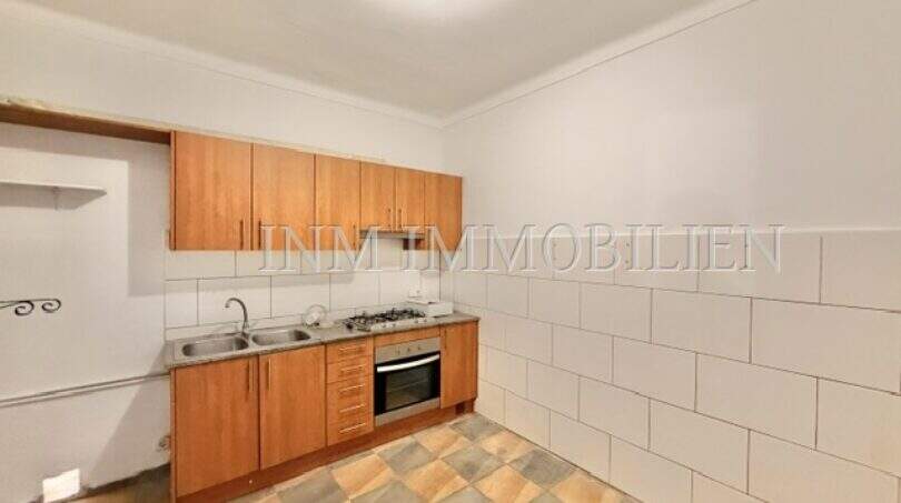 Kitchen needing renovation with wooden base cabinets, built-in stove, tile backsplash and checkerboard floor in Ses Cadenes.