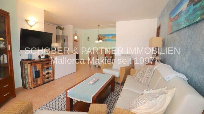Helles Wohnzimmer mit Rattanmöbeln, Holzcouchtisch und mediterraner Wanddekoration in Sa Coma