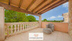 Überdachte Terrasse der Finca Santa Maria mit Holzbalken, Steinbalustrade und Blick ins Grüne.