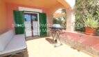 Terraza soleada con sofá, parrilla y contraventanas verdes del apartamento de 4 habitaciones en Cala Millor
