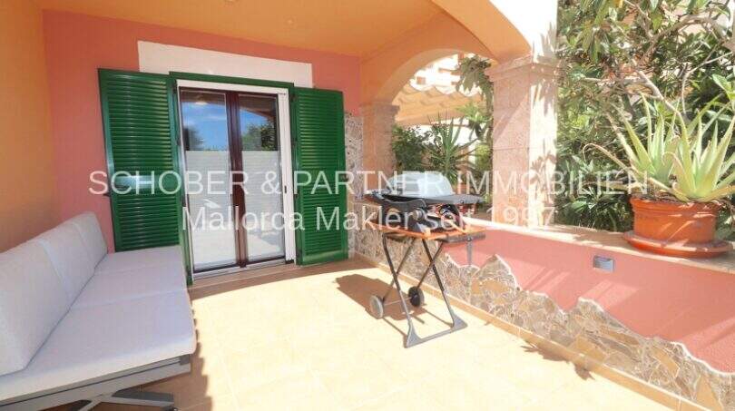 Terraza soleada con sofá, parrilla y contraventanas verdes del apartamento de 4 habitaciones en Cala Millor
