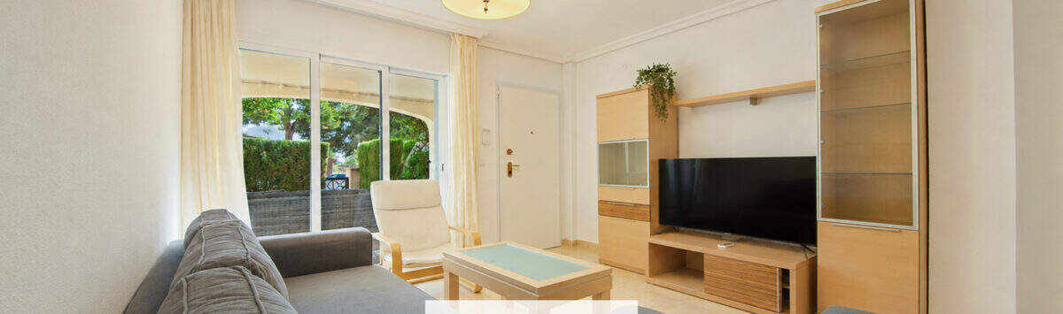 Helles Wohnzimmer der Erdgeschosswohnung Cala Antena mit Sofas, TV-Möbel und Zugang zur Terrasse.
