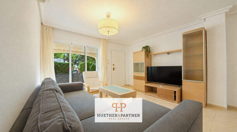 Helles Wohnzimmer der Erdgeschosswohnung Cala Antena mit Sofas, TV-Möbel und Zugang zur Terrasse.