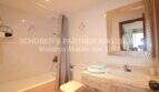 Helles Badezimmer mit Marmor-Waschtisch, Badewanne mit Dusche und elegantem Spiegel in Wohnung Sa Coma