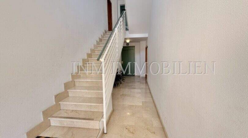 Heller Treppenaufgang mit Marmorböden und weißem Geländer in sonniger Wohnung in Palmanova
