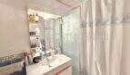 Badezimmer der Wohnung in Palma mit Waschbecken, Spiegel mit Ablage und Dusche mit Vorhang