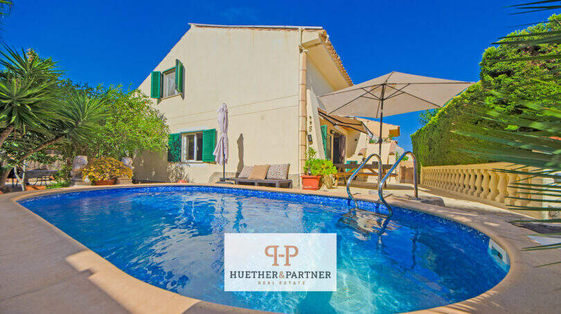 Außenbereich des Hauses in Cala Murada mit ovalem Pool, Sonnenterrasse und mediterranem Garten unter blauem Himmel.