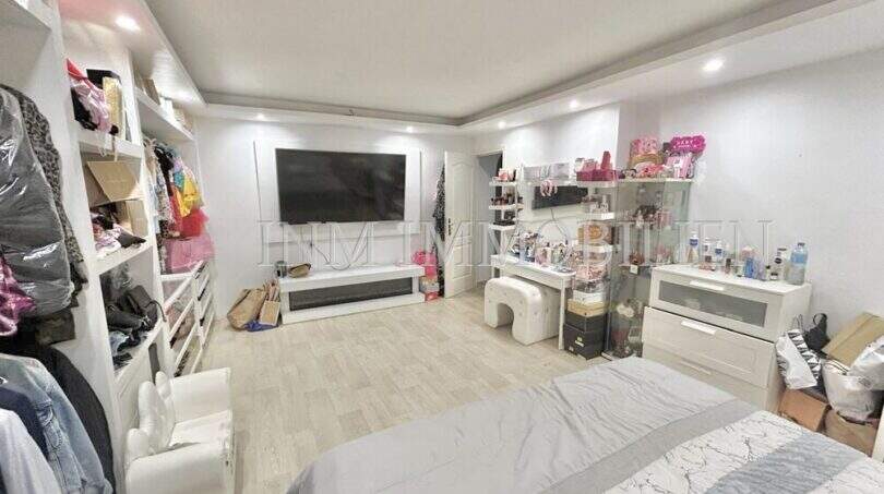 Helles Schlafzimmer mit Ankleidebereich, großem TV, Schminkplatz und Einbauregalen in Wohnung in El Arenal.