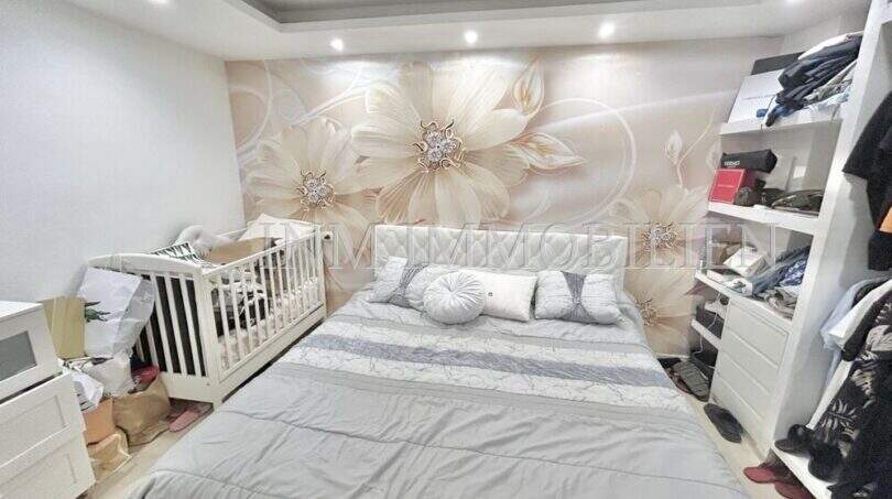 Schlafzimmer mit Doppelbett, Babybett, floraler Fototapete und Einbauregalwand in Wohnung in El Arenal