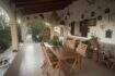Überdachte Terrasse der Finca mit Holztisch, Stühlen und dekorativen Wandobjekten im mediterranen Stil.