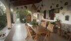 Überdachte Terrasse der Finca mit Holztisch, Stühlen und dekorativen Wandobjekten im mediterranen Stil.