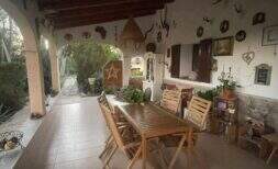 Überdachte Terrasse der Finca mit Holztisch, Stühlen und dekorativen Wandobjekten im mediterranen Stil.