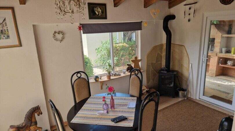 Gemütliches Esszimmer der Finca in Inca mit rundem Tisch, Holzofen und Gartenblick durchs Fenster.