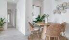Área de comedor luminosa con sillas de ratán, mesa de madera y decoración de pared en apartamento exclusivo en Palma de Mallorca.