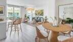 Área de estar-comedor luminosa con muebles de ratán, suelo de madera y grandes ventanas en apartamento exclusivo en Palma