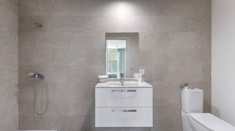 Baño moderno del apartamento de lujo en Palma con óptica de piedra natural gris, lavabo flotante y ducha a nivel del suelo.