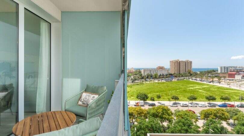 Balcón luminoso con muebles verde menta y vista al mar del apartamento exclusivo en Palma de Mallorca