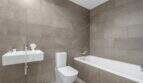 Baño moderno con azulejos con óptica de piedra gris, bañera empotrada, WC y lavabo montado en la pared en apartamento en Palma