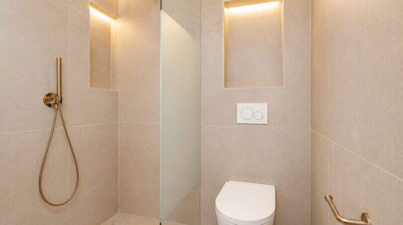 Modernes Badezimmer mit begehbarer Dusche, Wand-WC und goldenen Armaturen im Designer-Duplex Palma