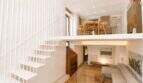 Offenes Duplex-Wohnzimmer mit weißer Designtreppe, Galerie, Kamin und hellem Holzboden in Palma