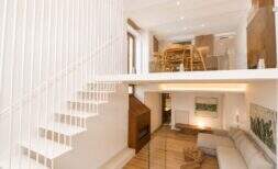 Offenes Duplex-Wohnzimmer mit weißer Designtreppe, Galerie, Kamin und hellem Holzboden in Palma