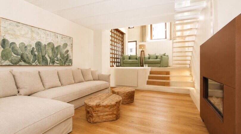 Helles Wohnzimmer mit Leinensofa, Naturholz-Couchtischen, Kaktus-Kunstwerk und Treppe zum Obergeschoss