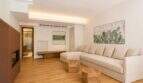 Helles Wohnzimmer mit cremefarbenem L-Sofa, Holzboden, Kaktus-Kunstwerk und modernem Kamin im Designer-Duplex Palma