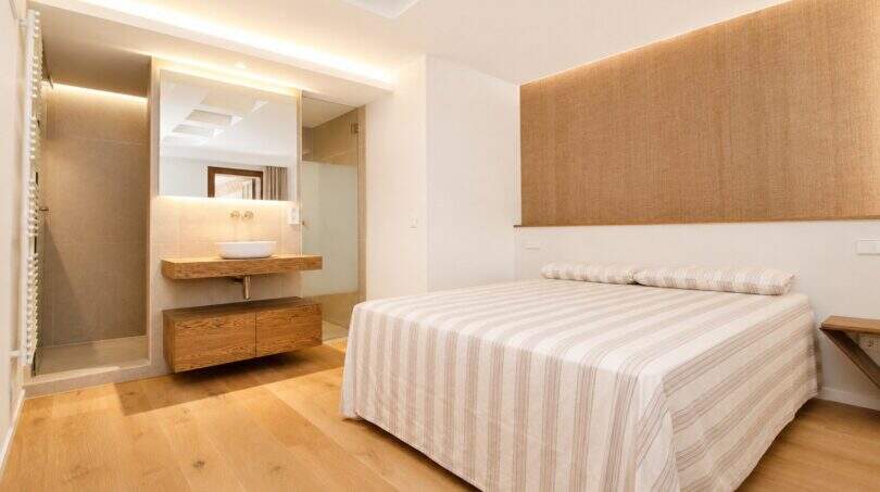 Helles Schlafzimmer mit Doppelbett, Holzboden und offenem Badezimmer mit Waschtisch im Designer-Duplex Palma