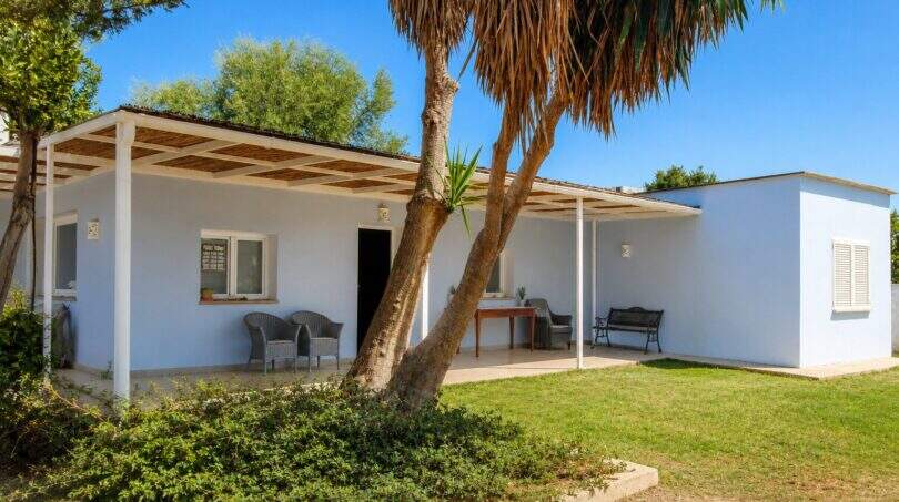 Weiße Finca-Außenansicht mit überdachter Terrasse, Palme und gepflegtem Garten in Palma de Mallorca