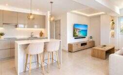 Offener Wohn-Küchenbereich des Penthouses in El Arenal mit moderner Kücheninsel, Holzmöbeln und hellem Fliesenboden.
