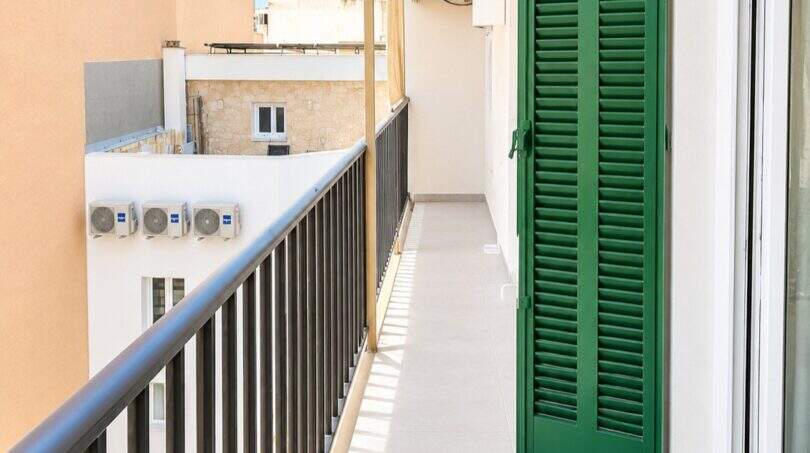 Estrecho balcón con persianas verdes, barandilla negra y vistas a la ciudad en el moderno ático El Arenal